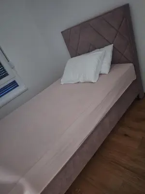 a bed with a white pillow on top of it at SD apartman - Trn in Ivišovo Greblje