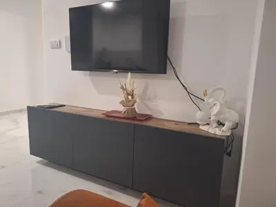 a black cabinet with a television on a wall at SD apartman - Trn in Ivišovo Greblje