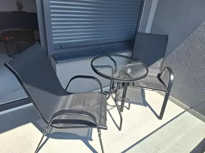 a glass table and two chairs on a balcony at SD apartman - Trn in Ivišovo Greblje