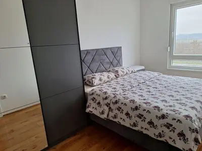 a bedroom with a bed and a large window at SD apartman - Trn in Ivišovo Greblje
