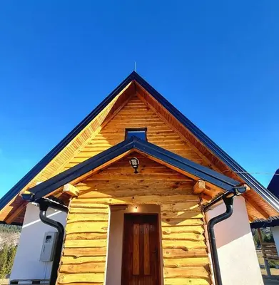 a wooden house with a door and a blue sky at Woodenhouse Ede Vlasic in Kutlovac