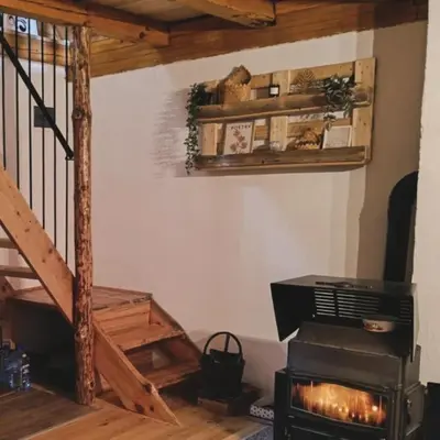 a living room with a stove and a staircase at Woodenhouse Ede Vlasic in Kutlovac