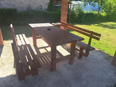 a wooden table and two chairs sitting next to a picnic table at Apartman Orijent in Kulen Vakuf