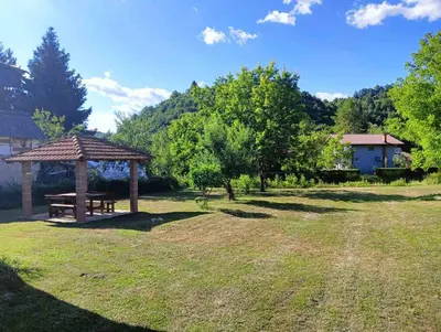 a picnic table and a gazebo in a field at Apartman Orijent in Kulen Vakuf