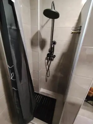 a bathroom with a shower with a black shower curtain at Domus Foresta Apartmani in Brdo