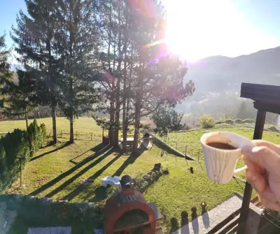 a person holding a cup of coffee in a field at Domus Foresta Apartmani in Brdo