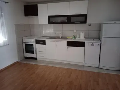 a kitchen with white appliances and a wooden floor at Apartman Bojan in Prnjavor