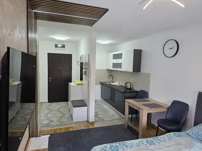 a room with a bed and a kitchen with a table at Apartman Garden 44 in Doboj