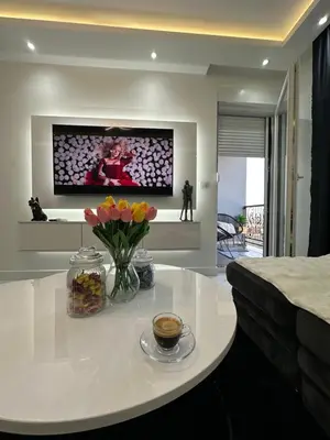 a living room with a table with flowers and a tv at Apartment Aristos in Modriča
