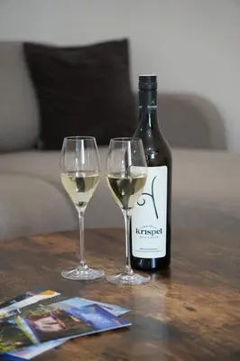 two glasses of white wine next to a bottle of wine at Apartments NIM in Jajce