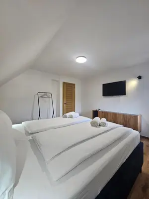 a bedroom with a large white bed with a flat screen tv at Apartments NIM in Jajce