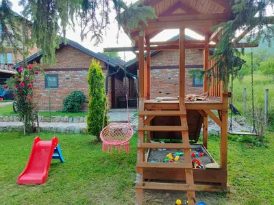 a play area with a wooden play house and a playground at Bungalovi Narandža Ramsko jezero