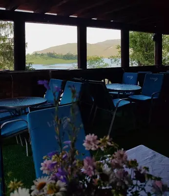 a row of tables and chairs with mountains in the background at Bungalovi Narandža Ramsko jezero