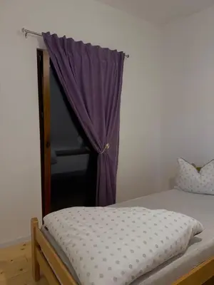 a bedroom with a bed and a window with purple curtains at Vikendica Diva