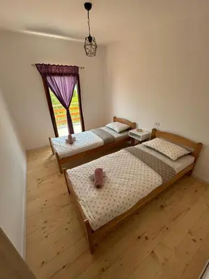 two beds in a room with a window at Vikendica Diva