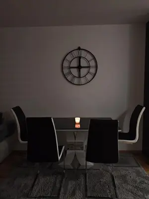 a table and chairs in a room with a clock on the wall at Urban escape in Doboj