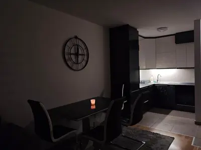 a kitchen with a table and chairs and a clock on the wall at Urban escape in Doboj