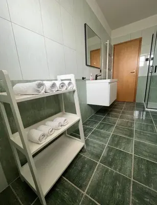 a bathroom with a sink and a shelf with towels at Apartman Delminium in Tomislavgrad