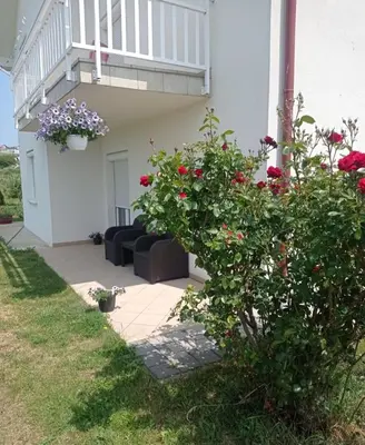 a house with a balcony and a couch and flowers at Apartman Delminium in Tomislavgrad