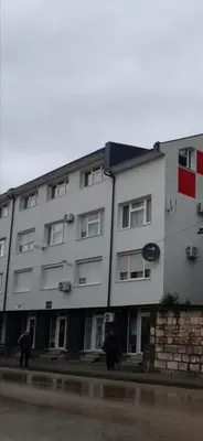 a white building with people walking in front of it at Apartman KULA Livno in Livno