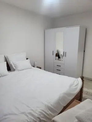 a bedroom with a large white bed and a cabinet at Apartman MM in Bihać