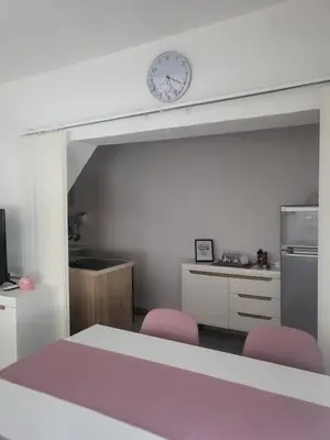 a kitchen with two pink chairs and a clock on the wall at Apartman MM in Bihać