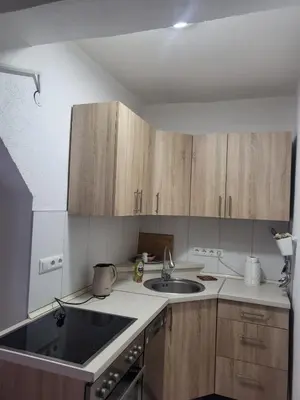 a small kitchen with a sink and wooden cabinets at Apartman MM in Bihać