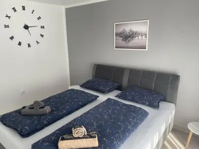 a bedroom with two beds and a clock on the wall at Apartman BOBA in Jajce
