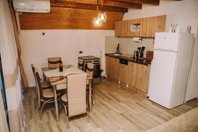 a kitchen with a table and a white refrigerator at Vikendica Buzadzija M&N
