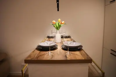 a table with wine glasses and a vase of flowers at Apartman Nikola in Livno