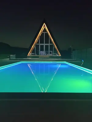 a pyramid shaped house with a blue swimming pool at night at Villa Rustic