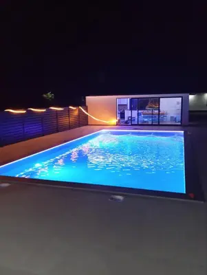 a swimming pool at night with a tv on top at Villa Rustic