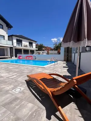 a chair and an umbrella next to a swimming pool at White house Paradise in Bihać