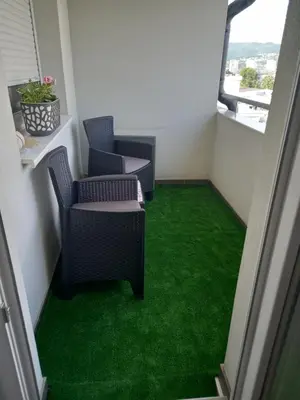 a room with green carpet and chairs on a balcony at Apartman Jana 2 in Doboj