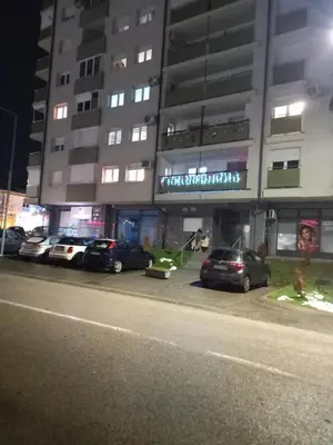 a parking lot with cars parked in front of a building at Apartman Jana 2 in Doboj