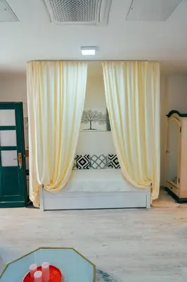 a bedroom with a bed with yellow curtains and a table at Apartman Suada in Fojnica