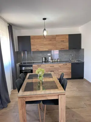 a kitchen with a wooden table with chairs and a kitchen with a stove at Apartman David in Jajce