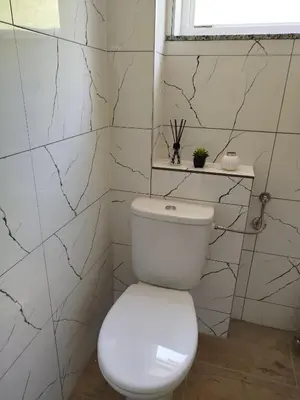 a white toilet in a bathroom with marble tiles at Apartman David in Jajce