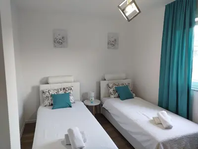 two beds in a room with blue curtains at Apartman David in Jajce