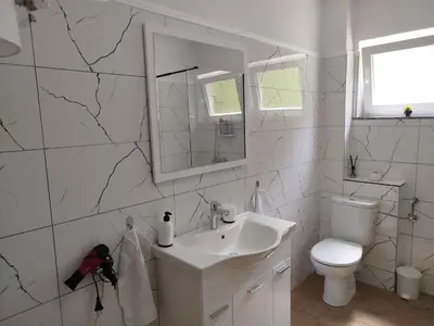 a white bathroom with a sink and a toilet at Apartman David in Jajce
