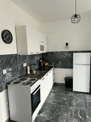 a kitchen with white cabinets and a stove and a refrigerator at TriM Apartments in Travnik