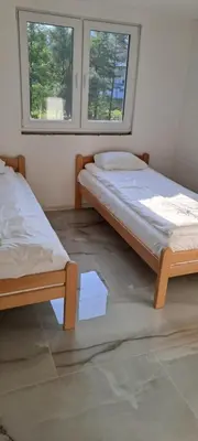 two beds in a room with two windows at Apartman Aydan in Jajce