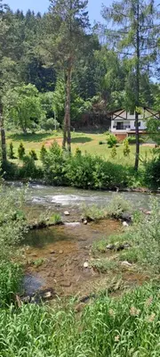 a creek in a field with a house in the background at Apartman Aydan in Jajce