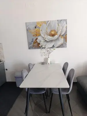 a white dining room table with chairs and a flower painting at Relax 2 in Bosanska Dubica
