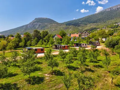 a village with trees and mountains in the background at Rama holiday resort in Prozor