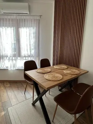 a dining room table with chairs and a window at Apartman Palazzo in Bosanska Krupa