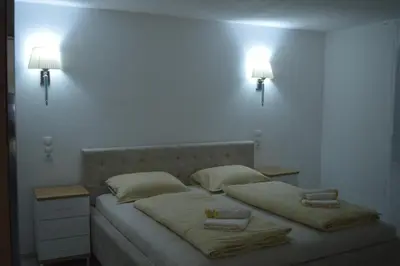 a bed with two pillows and two lights on the wall at Apartman Amela Deluxe in Kulen Vakuf