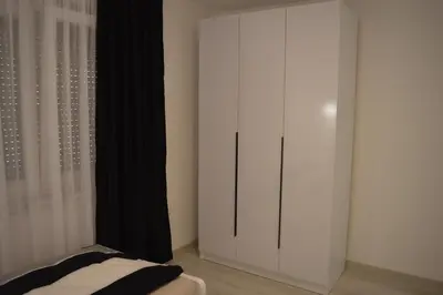a bedroom with a large white cabinet with black curtains at Apartman Amela Deluxe in Kulen Vakuf