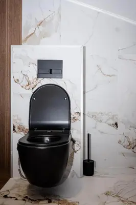 a black toilet in a bathroom with marble walls at Apartman 101 in Visoko