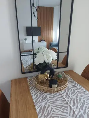 a table with a basket of flowers and a mirror at Apartman Nina Residence Banja Luka in Banja Luka